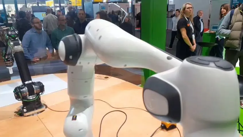 White lightweight robot arm performing a contact task at a trade fair stand