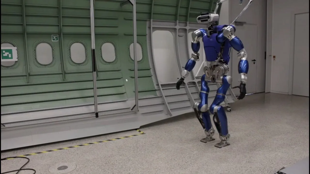 Blue humanoid robot walking in an aircraft fuselage mock-up